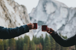 Two cups clinking by a mountain.