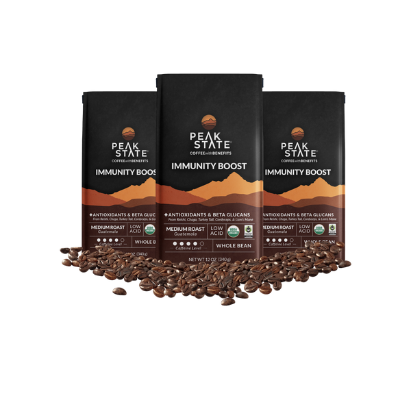 3x 12oz bags of Peak State's Immunity Boost whole bean coffee surrounded by coffee beans.