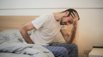 Man holding his head on bed. 