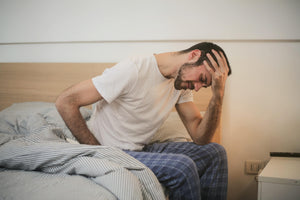 Man holding his head on bed. 